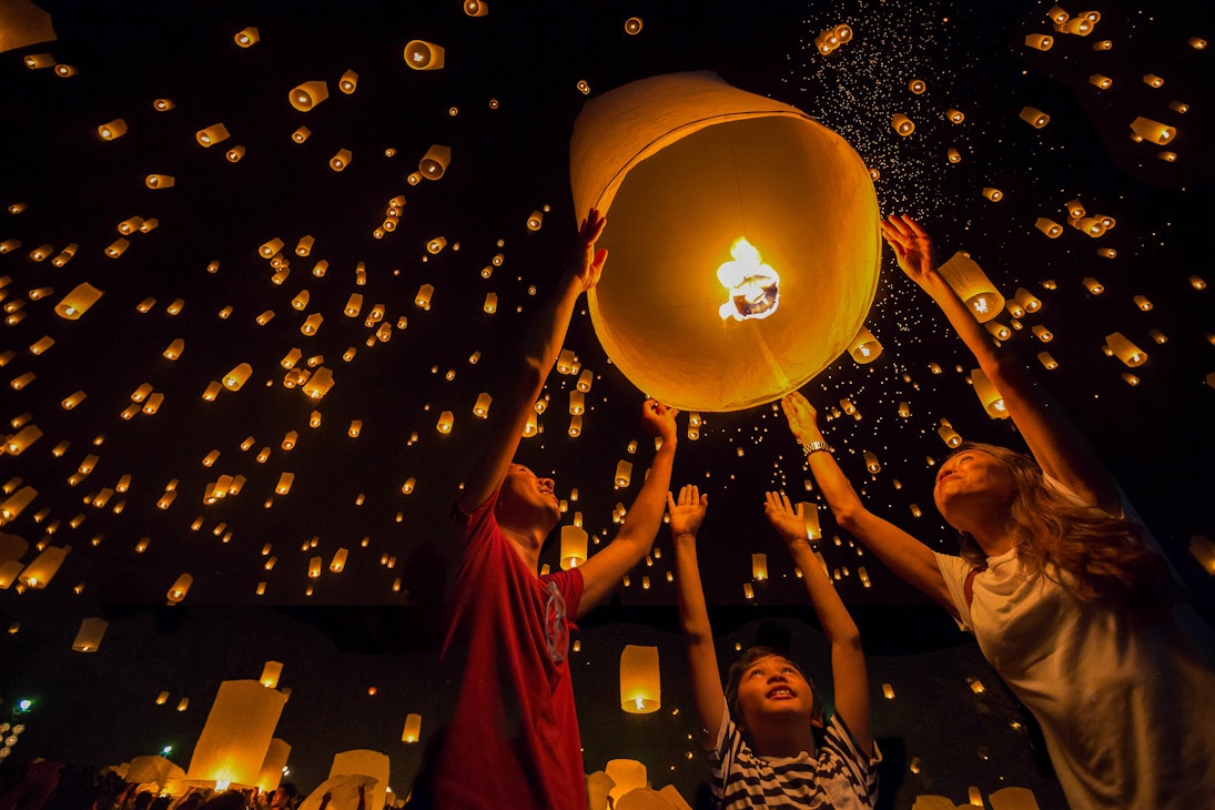 Thai family releasing paper lanterns to worship buddha's relics in Yi Peng Festival Chiangmai.